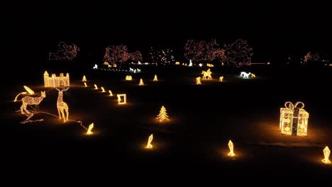 A-drone-footage-of-Aawinter-wonderland-created-with-festive-Christmas-lights,-featuring-deer,-gift-boxes,-and-evergreen-trees