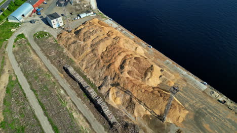 Huge-piles-of-sawdust-on-coast-for-ship-import-or-export,-aerial-view