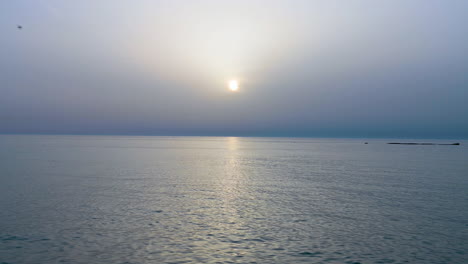 Ruhige-Wasserwellen-Auf-Dem-Meer-Ozean-über-Nebligen-Wolken-Himmelshintergrund-Am-Sonnenaufgang-Morgen