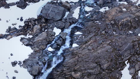 Aerial-orbiting-shot-of-a-small-waterfall-flowing-through-the-Buar-Valley-Glacier