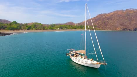 A-monohull-sailing-yacht-anchored-in-a-calm-water-bay-in-Guacamaya,-Costa-Rica-with-no-other-sailing-vessels-anywhere-around