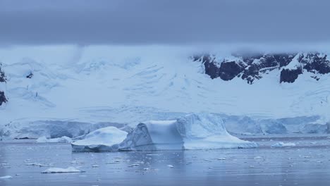 Iceberg-and-Winter-Mountains-in-Cold-Blue-Landscape-Scenery-in-Antarctica-with-Ice-and-Glacier-in-Dramatic-Beautiful-Coastal-Scene-on-Coast-on-Antarctic-Peninsula,-Moody-Blue-Atmosphric