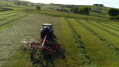 Epic-Drone-shot,-flying-over-and-past-a-farmer-working-his-land-in-a-tractor,-on-a-West-Yorkshire-farm-during-the-evening