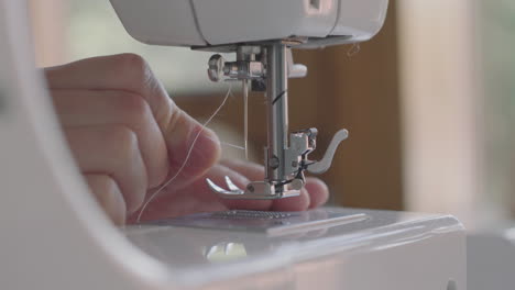 Seamstress-Inserts-The-Thread-Into-The-Needle-Of-A-Sewing-Machine---closeup-shot