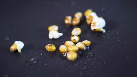 Popcorn-popping,-exploding-in-slow-motion-in-pan,-close-up-detail-shot