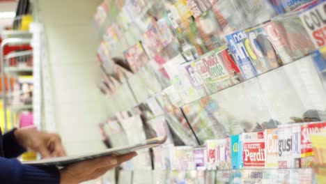 Unrecognizable-woman-picking-the-magazine-from-the-newsstand