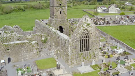 Claregalway-Friary-cemetery-on-monastery-grounds-on-bright-sunny-day,-aerial-pan