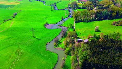 Luftaufnahme-Eines-Serpentinenflusses,-Der-Durch-Grüne-Felder-Und-Wälder-Fließt