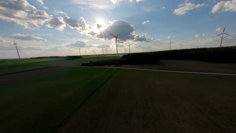 Agriculture-fields-and-wind-turbines-spin,-aerial-FPV-flyby