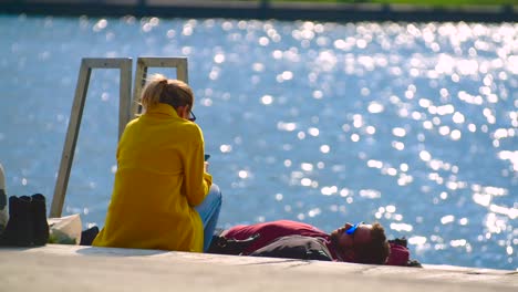 Happy-young-couple-sunbathing-Danube-river-bank-on-sunny-day,-Vienna