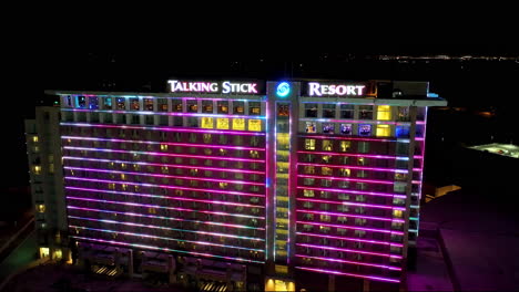 Drone-shot-of-the-Talking-Stick-Resort-at-night-with-the-light-up-wall-pulsing-different-colors