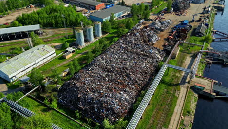 Piles-of-old-recycled-metal-stored-and-ready-for-export,-aerial-orbit-view