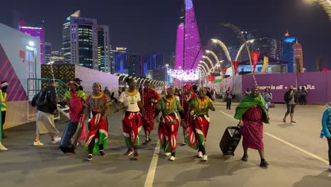 Afrikaner-Aus-Kenia,-Männer-Und-Frauen-Tanzen-Fröhlich-Zusammen-In-Farbenfroher-Kleidung,-Kostüm,-Mode,-Lächeln,-Frieden-Und-Musik-Auf-Einem-Straßenfest-In-Doha,-Katar,-Corniche,-Strand,-Gehweg,-Licht,-FIFA