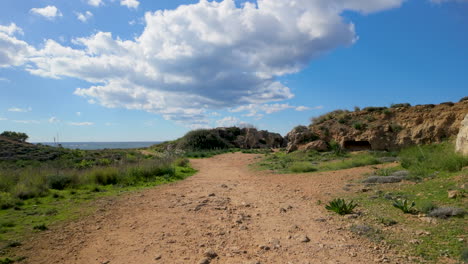 Ein-Feldweg,-Der-Durch-Die-Archäologische-Stätte-Der-Königsgräber-In-Paphos-Führt,-Mit-Antiken-Ruinen-Und-Viel-Grün-Auf-Beiden-Seiten