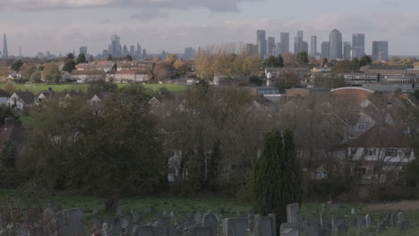 Canary-Wharf,-London-Cityscape-from-Cemetery,-gravestones-in-foreground,-UK-Financial-Crash