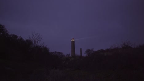 Lighthouse-of-the-frisian-north-sea-island-Borkum-sending-beams-of-light-illuminating-the-dark-night-sky