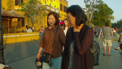 Locals-and-tourists-walking-at-sunset-in-old-town-of-Hoi-an,-Vietnam