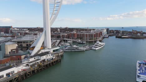 Low-flight-alongside-base-of-Spinnaker-Tower,Gun-Wharf-Quays-Portsmouth-over-superyachts-in-marina-showing-waterfront-and-shopping-centre