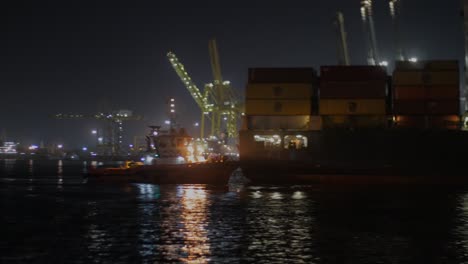 Filmische-Bewegte-Aufnahme,-Die-Nachts-An-Einem-Containerschiff-Vorbeifährt,-Und-Blick-Auf-Den-Hafen,-Autonomer-Hafen-Von-Dakar---Port-Autonome-De-Dakar,-Senegal