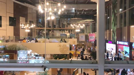 View-Through-Glass-Wall-Of-Shoppers-Dining-At-The-Restaurant-Inside-Arribat-Center-Shopping-Mall-With-Modern-Interiors