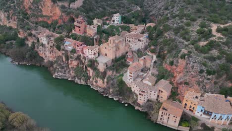 Miravet,-a-picturesque-town-with-colorful-houses-perched-on-a-cliff-by-the-river,-aerial-view