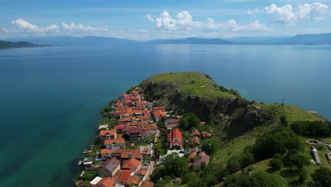 Pueblo-De-Lin-En-El-Borde-Rocoso-De-La-Península-A-Lo-Largo-De-La-Hermosa-Costa-Del-Lago-Ohrid,-Rodeado-De-Aguas-Tranquilas-Color-Esmeralda