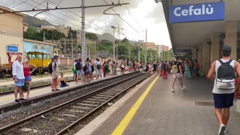 Gente-Cruzando-Una-Vía-Férrea-En-El-Andén-De-Una-Estación-De-Tren-Abarrotada-En-Italia