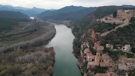 Historic-Miravet-town-with-medieval-castle-and-the-Ebro-River-flowing-through-lush-Spanish-countryside