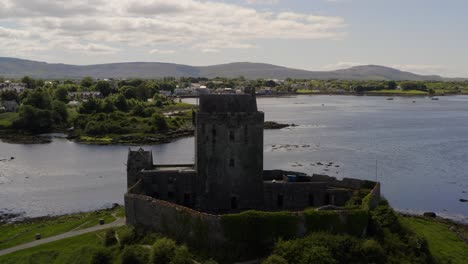 Dynamic-aerial-of-Kinvara-tower-house,-enclosed-by-its-historic-protective-bawn