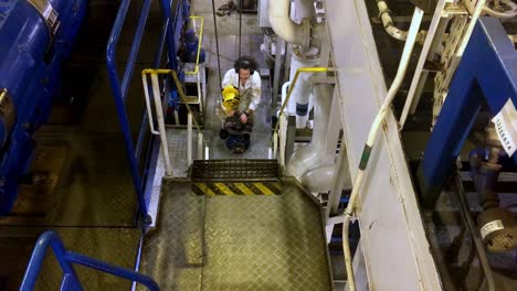 Person-working-on-industrial-equipment-and-machinery-inside-ship