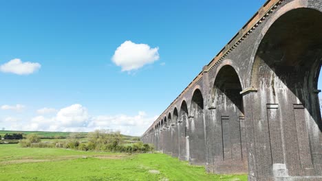 Low-drone-flight-alongside-the-arches-of-Welland-Viaduct-Northamptonshire,-also-known-as-the-Harringworth-and-Seaton-Viaduct-on-sunny-day