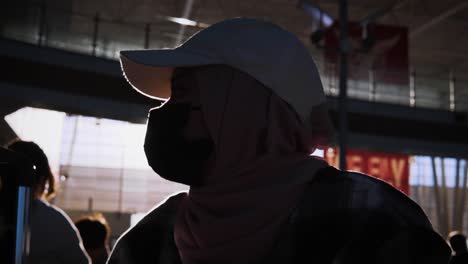 Silhouette-Hijabi-muslim-girl-daydreaming-at-the-airport-with-sun-flare,-ultra-slow-motion