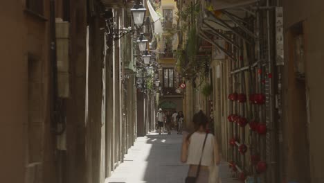 Ein-Tourist-Läuft-Im-Vordergrund-Einer-Schmalen-Straße-In-Barcelona,-Spanien,-Mit-Fußgängern-Im-Hintergrund,-Die-Das-Abenteuer-Der-Stadterkundung-Betonen