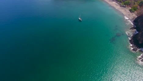 Video-Aéreo-Volando-Hacia-Abajo-En-Un-Velero-Monocasco-Anclado-En-Una-Bahía-Tranquila-Y-Vacía-Que-Se-Inclina-Para-Revelar-Una-Hermosa-Playa-De-Arena-En-El-Paraíso