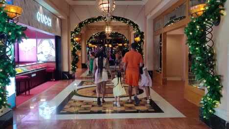 Brillante-Hotel-De-Lujo-De-Atlantis-En-Bahamas-Con-Gente-Caminando-En-Un-Salón-Decorado-De-Navidad-Cerca-De-Una-Tienda-De-Gucci