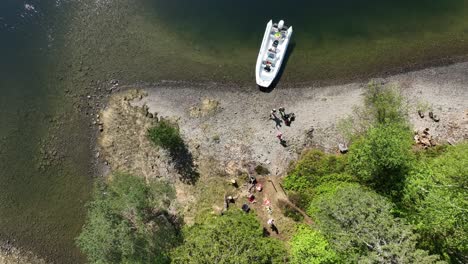 Touristenfamilie-Genießt-Mittagspause-Auf-Einer-Versteckten-Insel-Während-Fjordsafari,-Top-Down-Luftaufnahme