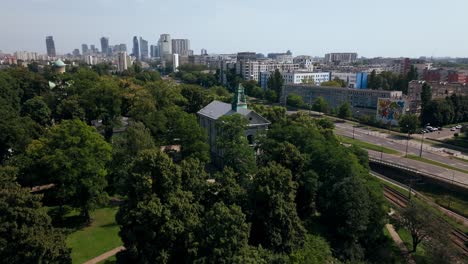 Vista-Aérea-De-Los-Suburbios-Occidentales-De-Varsovia,-Polonia,-La-Iglesia-Católica-Y-Ortodoxa,-El-Tráfico-Callejero,-Los-Edificios-Y-El-Centro-De-La-Ciudad-En-El-Horizonte