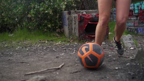 Closeup-of-girl-dribbling-soccer-ball-around-graffiti-rocks,-practicing-soccer-drills,-slow-motion-tracking
