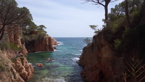 Panoramic-slowmo-view-of-a-cliff-rocky-shore-in-Costa-Brava-Catalonia,-blue-and-green-water,-mediterranean