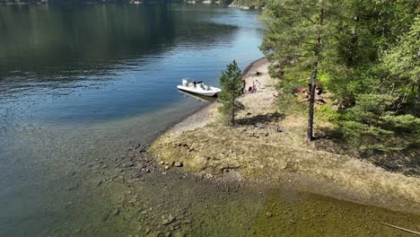 Aerial-reveal-of-Tourist-Family-on-RIB-safari-having-Lunch-on-Hidden-Island-in-Fjord