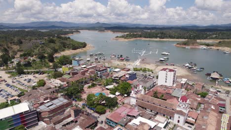 Guatapé,-colombia,-showcasing-the-vibrant-town-and-serene-lake-with-boats,-aerial-view