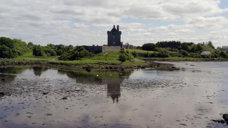 Wunderschöne-Gespiegelte-Dolly-Aufnahme-Von-Dunguaire-Castle-Mit-Anmutig-Gleitenden-Schwänen