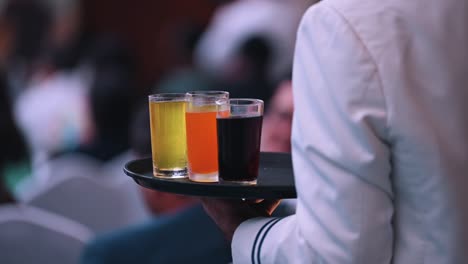 A-waiter-holds-a-tray-of-different-soft-drinks-in-glasses-during-an-event