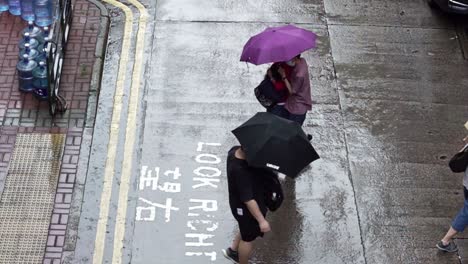 People-Crossing-Street-Under-Umbrellas-in-Rain,-Mong-Kok,-Hong-Kong,-Slow-motion