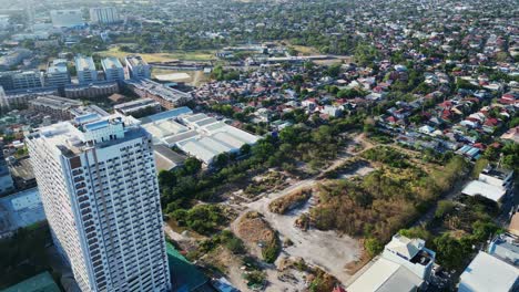 Flyover-drone-shot-of-developing-city-grounds-with-buildings-and-subdivisions-in-Alabang,-Muntinlupa-City,-Philippines