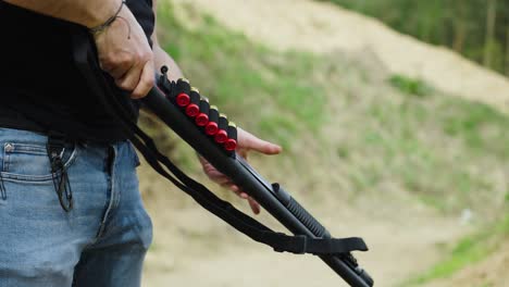 Guy-hold-black-shotgun-weapon-at-outdoor-Olesko-shooting-range,-Czechia