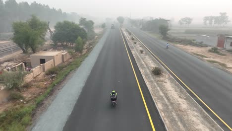Motorbike-on-Punjab-highway,-Pakistan---aerial-tracking-shot
