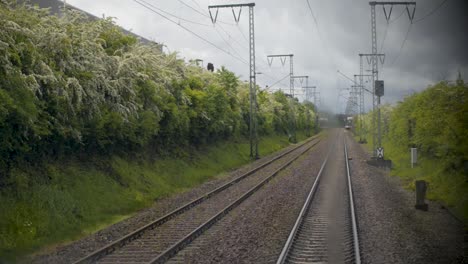 POV-Aufnahme-Von-Bahngleisen,-Die-Nach-Vorne-Führen,-Mit-Herannahendem-Zug,-Bewölkter-Himmel