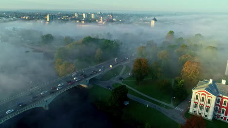 Aerial-drone-shot-of-thick-fog-covering-the-city-of-Jelgava,-Latvia-during-morning-time