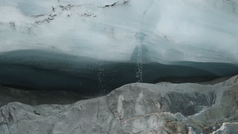 Water-dripping-down-from-ice-in-a-glacier-lake-at-Brewster-Track-in-Mount-Aspiring-National-Park,-New-Zealand